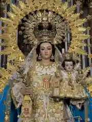 Nuestra Señora de las Mercedes de Mairena del Aljarafe en primer plano, con el Niño Jesús, ráfaga dorada y manto azul.